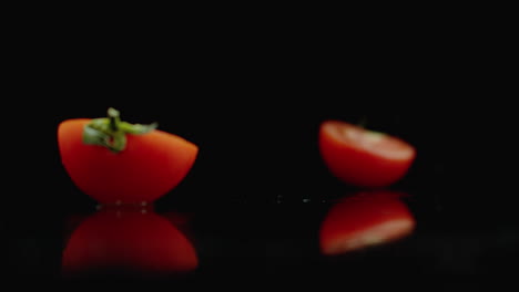 Geschnittene-Rote-Tomaten-Fallen-In-2-Teile-Glas-Mit-Wasserspritzern-In-Zeitlupe-Auf-Dunklem-Hintergrund